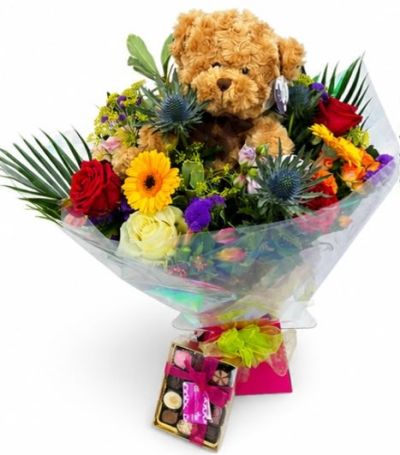 Truly Scrumptious - A delightful gift set featuring a colourful hand-tied bouquet, an adorable teddy bear and a box of chocolates, perfect for making any celebration extra special.